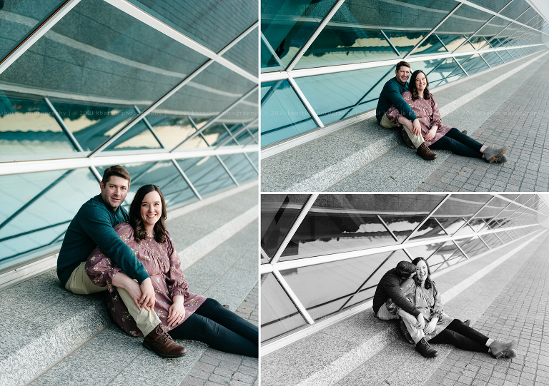 a couple poses in front of a wall of glass during their milwaukee engagement photos